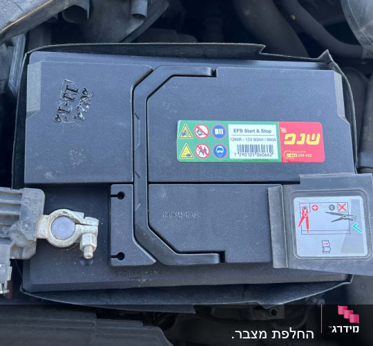 מצבר רכב עם תוויות אזהרה וחיבורים חשמליים